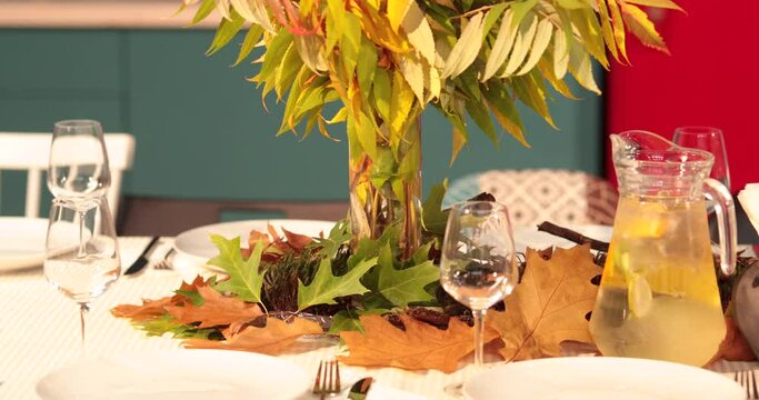 A close-up shot of a table set in an autumn style. Table setting-decoration of a large table with leaves on an autumn theme for receiving guests.