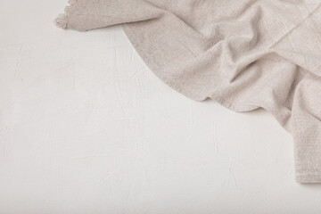 Obraz premium Kitchen towel on a light textured background. Kitchen utensils and textile napkin. A stack of cotton towels on the table. Home decor. Tablecloth for the table. Copy space for text. Mockup for design.