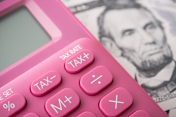 Calculator in focus on tax minus rate button and US dollar banknote background. United States of...