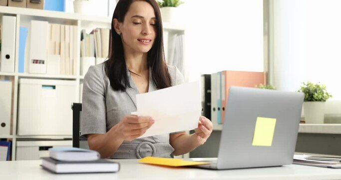 Woman taking letters out of yellow envelope and rejoicing in office 4k movie. Winning lottery concept