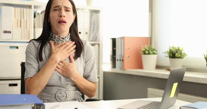 Businesswoman with metal chain around her neck coughing at table in office 4k movie. Seasonal sore throat diseases concept