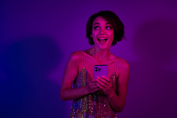 Photo of positive surprised lady browsing festive events ads in nightclub using cell gadget isolated colorful neon background