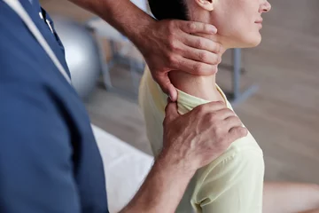 Foto auf Acrylglas Massagesalon Close-up of manual therapist massaging pain neck of young woman during therapy in clinic