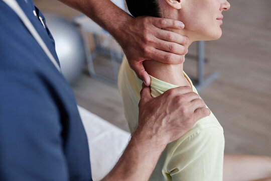 Close-up of manual therapist massaging pain neck of young woman during therapy in clinic
