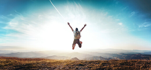 Happy man with arms up jumping on the top of the mountain - Successful hiker celebrating success on the cliff - Life style concept with young male climbing in the forest pathway - Powered by Adobe