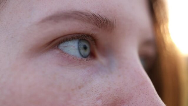 macro of female eye at sunset. close-up of blinking girl's eyes. blue eye beautiful female eyes. lifestyle