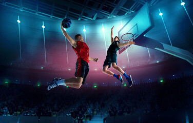 Dynamic image of young men, professional basketball players in motion, in a jump with ball under...