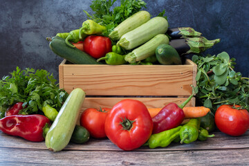 Various vegetables on a wooden table. Tomato, Green Pepper, Red Pepper, Parsley, Carrot, Eggplant, Cucumber, Zucchini.