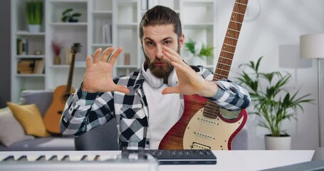 Caucasian male musician use musical instrumentlooking in camera and shooting video on mobile phone for vlog.