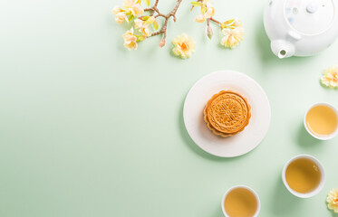 Chinese Mid-Autumn Festival concept made from mooncakes, tea and plum blossom on pastel background.