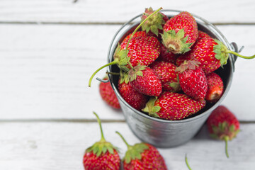 Strawberries in a small steel bucket on a white table