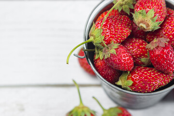Strawberries in a small steel bucket on a white table