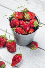 Strawberries in a small steel bucket on a white table