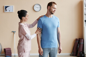 Obraz premium Professional therapist examining shoulder and back of patient in hospital