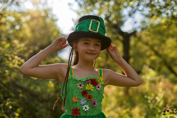 Cute leprechaun girl posing in a cylinder hair and green dress decorated with shamrock