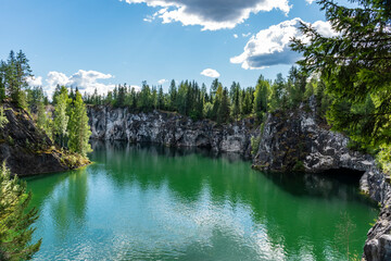Naklejka na ściany i meble A lake among rocks overgrown with coniferous forest
