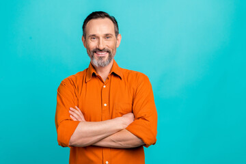 Photo of cheerful positive guy wear orange shirt smiling arms folded empty space isolated teal color background