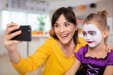 mother taking selfie with child wearing face paint