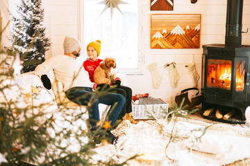 family dad and teenage boy sit near fireplace and having fun in living room of cozy winter house, Christmas and New Year holidays and vacation