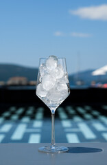 Drinking glass filled with ice cubes near swimming pool