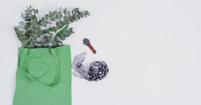 Video of green canvas bag with plant, scarf, watch, copy space on white background
