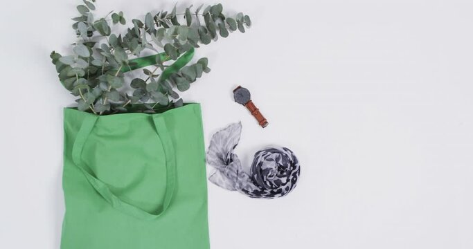 Video of green canvas bag with plant, scarf, watch, copy space on white background