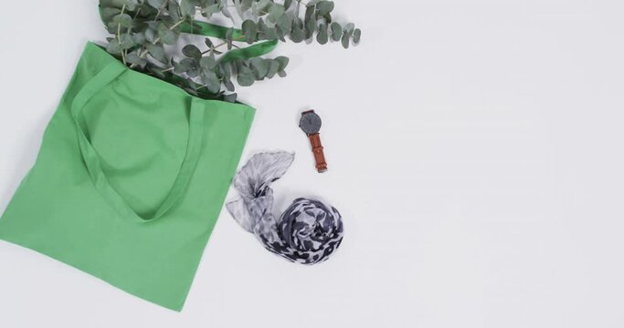 Video of green canvas bag with plant, scarf, watch, copy space on on white background