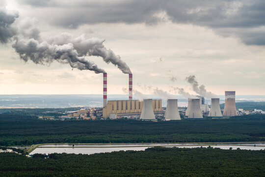 Aerial view of power plant, smoke from chimneys and open-cast coal mine in Belchatow under moody cloudy sky, Poland