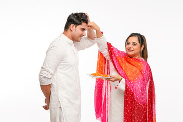 Indian brother and sister celebrating Raksha Bandhan or Rakhi festival. sister getting tika on...