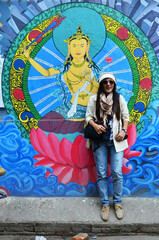 Obraz na płótnie Canvas Travelers thai women journey travel visit take photo with landmark street art graffiti painting and drawing design nepalese style on antique wall at thamel city on October 29, 2013 in Kathmandu, Nepal