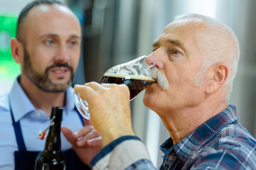senior man tasting beer in brewery