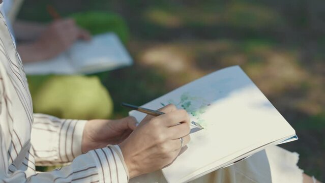 A person paints with watercolors in the park