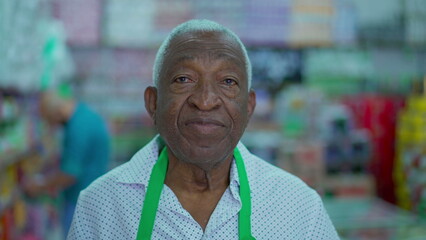 Portrait of a Black Brazilian senior employee of Grocery Store standing in aisle wearing uniform with neutral expression, looking at camera. job occupation concept