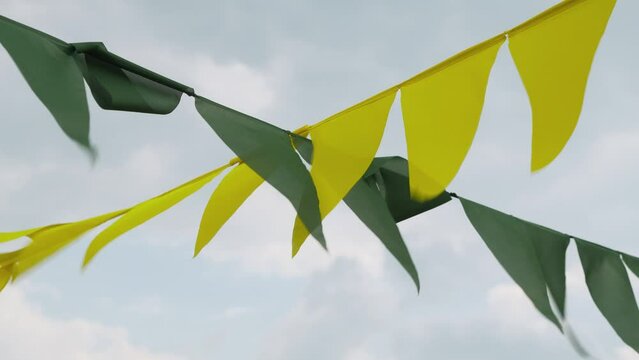 Triangular green and yellow flags on a rope on a sunny summer day