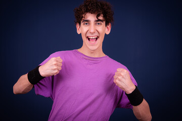 Healthy lifestyle. Funny emotional guy is doing fitness. Student posing on a blue background.
