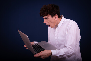 Funny emotional guy is preparing for exams. Student posing on a blue background.