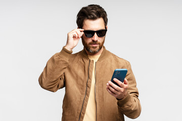 Portrait of serious bearded man in sunglasses holding mobile phone