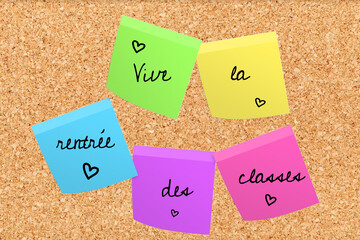 Long live back to school written in French in black font on different multicolored post-its with little hearts on a cork board