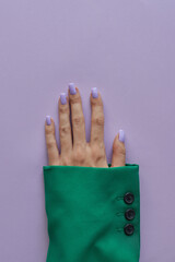Female's hand with trendy gelish manicure with nails of purple color. Green and purple colors - 627737122