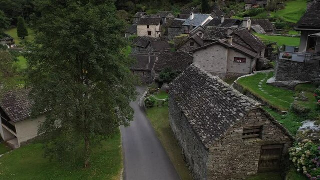 Aerial video of a man with a red coat walking in Cevio, Switzerland