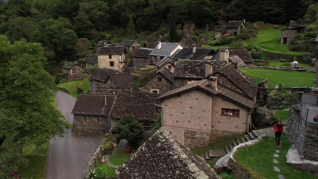 Aerial video of a man with a red coat walking in Cevio, Switzerland