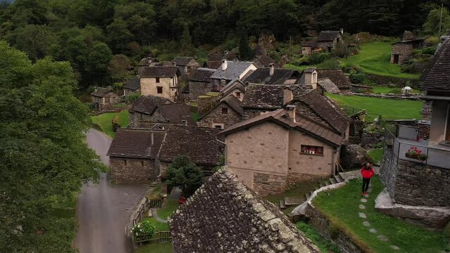 Aerial video of a man with a red coat walking in Cevio, Switzerland