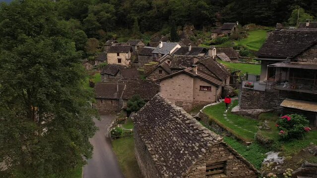 Aerial video of a man with a red coat walking in Cevio, Switzerland