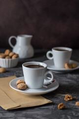Two cups of coffee, a milkjug and cookies on a dark background