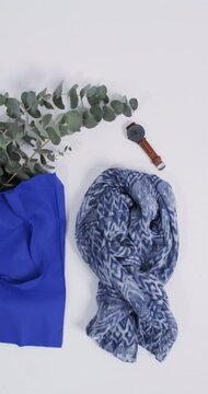 Vertical video of blue canvas bag with plant, scarf, watch, copy space on white background