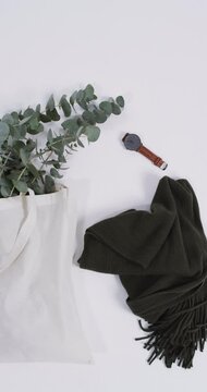Vertical video of white canvas bag with plant, scarf, watch, copy space on white background