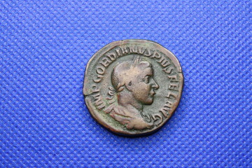Sestercio de Gordiano III, emperador romano, sobre fondo azul.