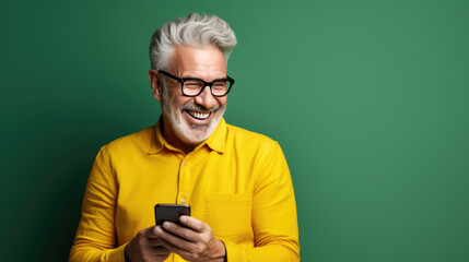 Middle-aged man is using a cell phone on a green background.