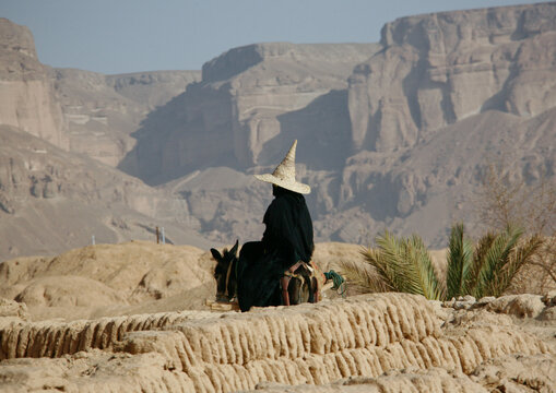Hadramout woman with a full black dress, gloves and a high hat; The high hats are supposed to bring fresh air to the head; Yemen;