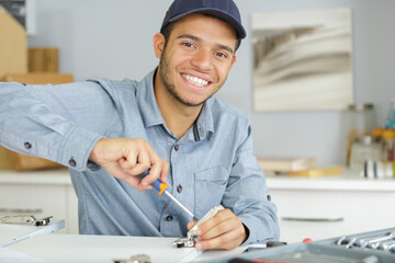 portrait of young man using screwdriver in kitchen